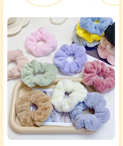 Flat lay of colorful plush hair scrunchies in various soft pastel tones on a tray