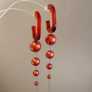 Macro shot of red gradient bead drop earrings with resin hooks on minimalist display stand
