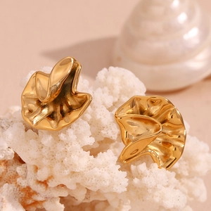 Artistic golden irregular crumpled petal stud earrings on white coral prop