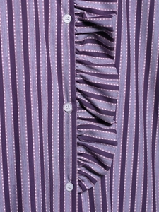 Detailed close-up of purple striped blouse with white polka dots and ruffle trim edges