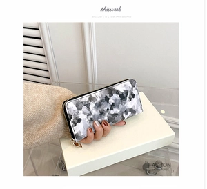 Detail of long marble print wallet for women with golden zipper and ink floral pattern