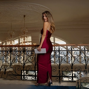Detail of elegant red high slit evening dress paired with silver marble clutch bag
