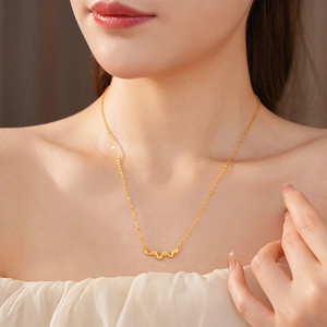Close-up of a vintage brushed gold wavy pendant necklace worn on a model's neck