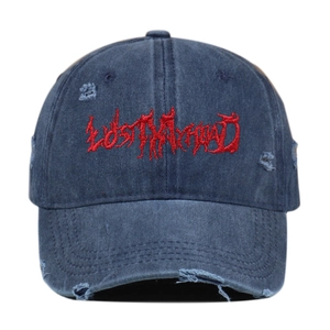 Detail of red Gothic embroidery and distressed ripped holes on blue denim baseball cap