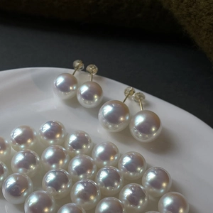 Macro shot of 925 silver pearl earrings with high luster on a white porcelain dish