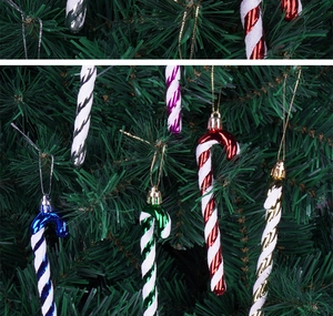Detail of candy cane Christmas ornaments with glitter stripes on green tree background
