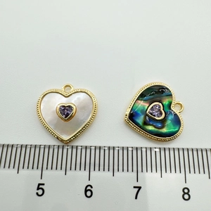 Detail view of 18K gold-plated heart charms with natural shell inlay and purple gem