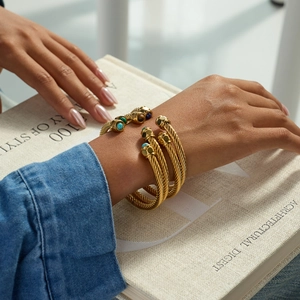 Elegant gold twisted cable bangle with malachite and tiger eye stones worn by a model