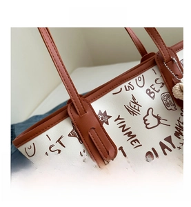 Close-up of graffiti print tote bag showing leather handles and fine stitching details