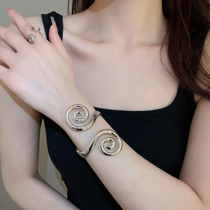 Detailed view of silver spiral cuff bracelet and matching ring on model with modern art design