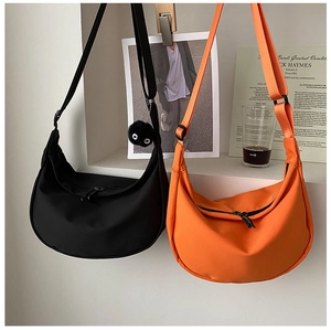Minimalist nylon crescent crossbody bag in black and orange hanging in a stylish setting