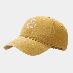 Detail view of ginger yellow baseball cap with a white embroidered smiley face