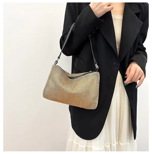 Detail of shimmering champagne gold rhinestone shoulder bag with black leather handle and zipper