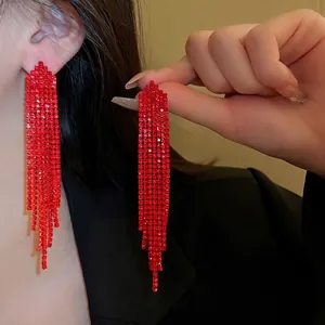 Long red tassel earrings with multiple rows of sparkling rhinestones worn by a model