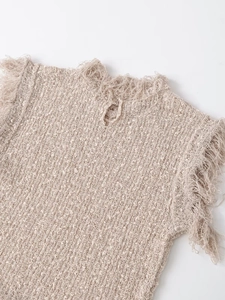 Close-up of beige knitted vest showing fringe edge detail and grainy fabric texture