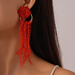 Detailed close-up of red flower tassel earrings with glass beads worn by a model