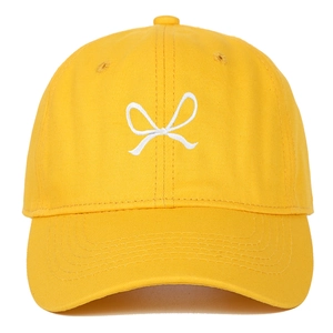 Detail of white ribbon bow embroidery on a bright yellow cotton canvas baseball cap