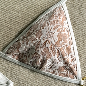 Detailed macro of floral lace triangle cup with white piping and nude lining
