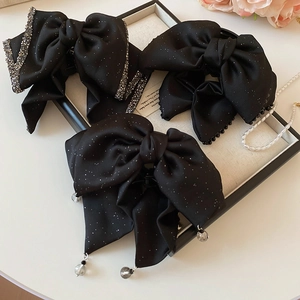 Detailed view of three black shimmering bow hair claws with crystal and pearl accents