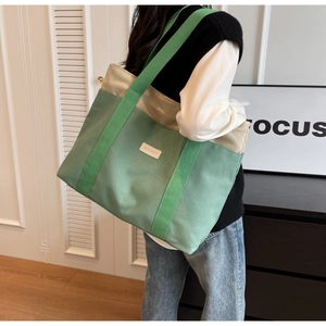 Detail of canvas tote bag with green and beige patchwork and branded woven label
