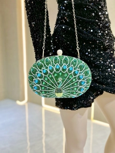 Close-up of a green peacock rhinestone clutch bag with gold chain and luxury crystals