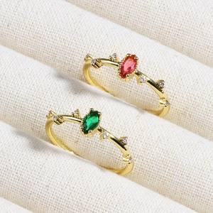 Close-up of luxury gold rings with red and green gemstones on white velvet jewelry tray