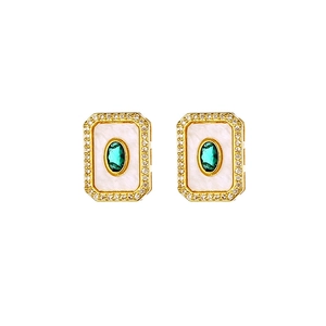 Close-up of 18K gold-plated earrings featuring emerald green zircons and diamond halo