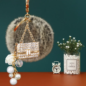 Detailed view of grey faux fur pompom keychain with crystal handbag and pearl charms