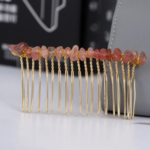 Dettaglio macro del pettine in metallo dorato con accenti di pietre di cristallo rosso