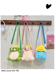 Three plush turtle crossbody bags in green pink and blue hanging on a wooden rack