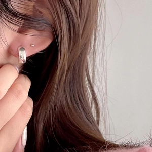Close-up of minimalist silver oval hoop earrings on a model showing polished finish
