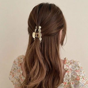 Golden alloy hair claw clip with cat eye stone beads on brown wavy hair