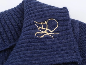 Macro shot of navy blue ribbed knit fabric with premium gold thread logo embroidery