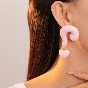 Detail showing oversized pink resin question mark earrings with a heart drop pendant