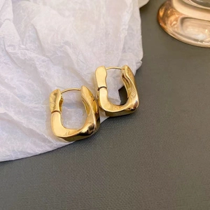 Orecchini quadrati a torsione placcati oro 18k vintage su carta ruvida bianca