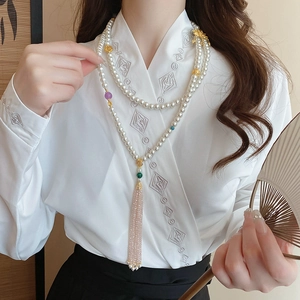 Detail of multilayer pearl necklace with pink tassel and gold accents on a white hanfu