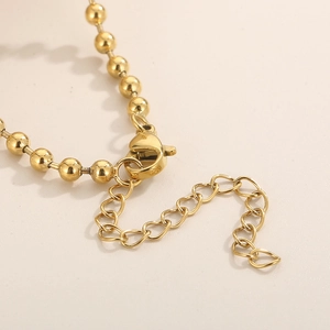 Détail de la chaîne d'extension dorée réglable et du fermoir mousqueton sur un collier