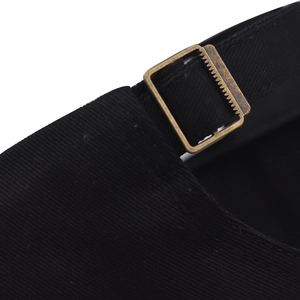 Detail of adjustable cotton strap and bronze metal buckle on black baseball cap