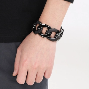 Close-up of a 30mm black Cuban link chain bracelet on a model wrist showing glossy finish