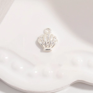 Macro shot of silver seashell pendant with tiny white zircon stones and hook detail