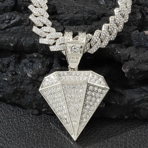 Silver iced-out cuban chain necklace with diamond-encrusted pyramid pendant on a rock