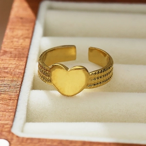 Macro shot of 18k gold heart ring with woven texture on a beige velvet jewelry box