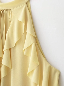 Detail shot of light yellow chiffon top featuring a halter neck and layered ruffles