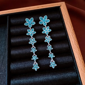 Vintage silver zircon flower drop earrings with blue stones on black velvet tray