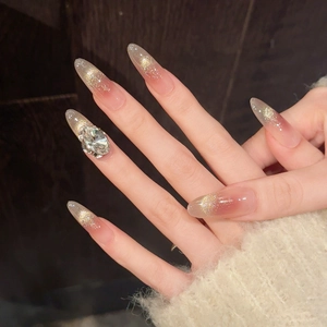 Detail of almond pink gradient press-on nails with golden glitter and a large crystal diamond