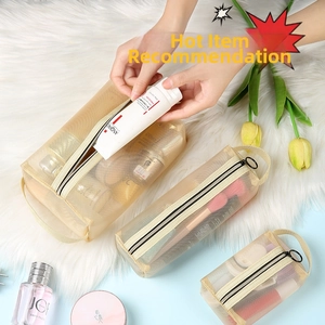 Three-piece beige mesh makeup bag set with zipper and handle on a soft white carpet