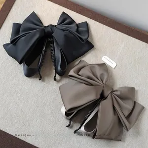 Detail of satin bow banana clips in black and champagne on a textured tray