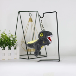 Close-up of grey plush dinosaur keychain with yellow spine and metal ring on display stand