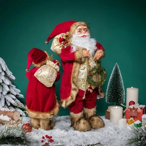 Figurines de Père Noël en tissu rouge et or sur neige avec sapin et bougies