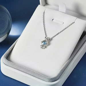 Detail of bunny necklace with moonstone pendant in a jewelry box on starry background